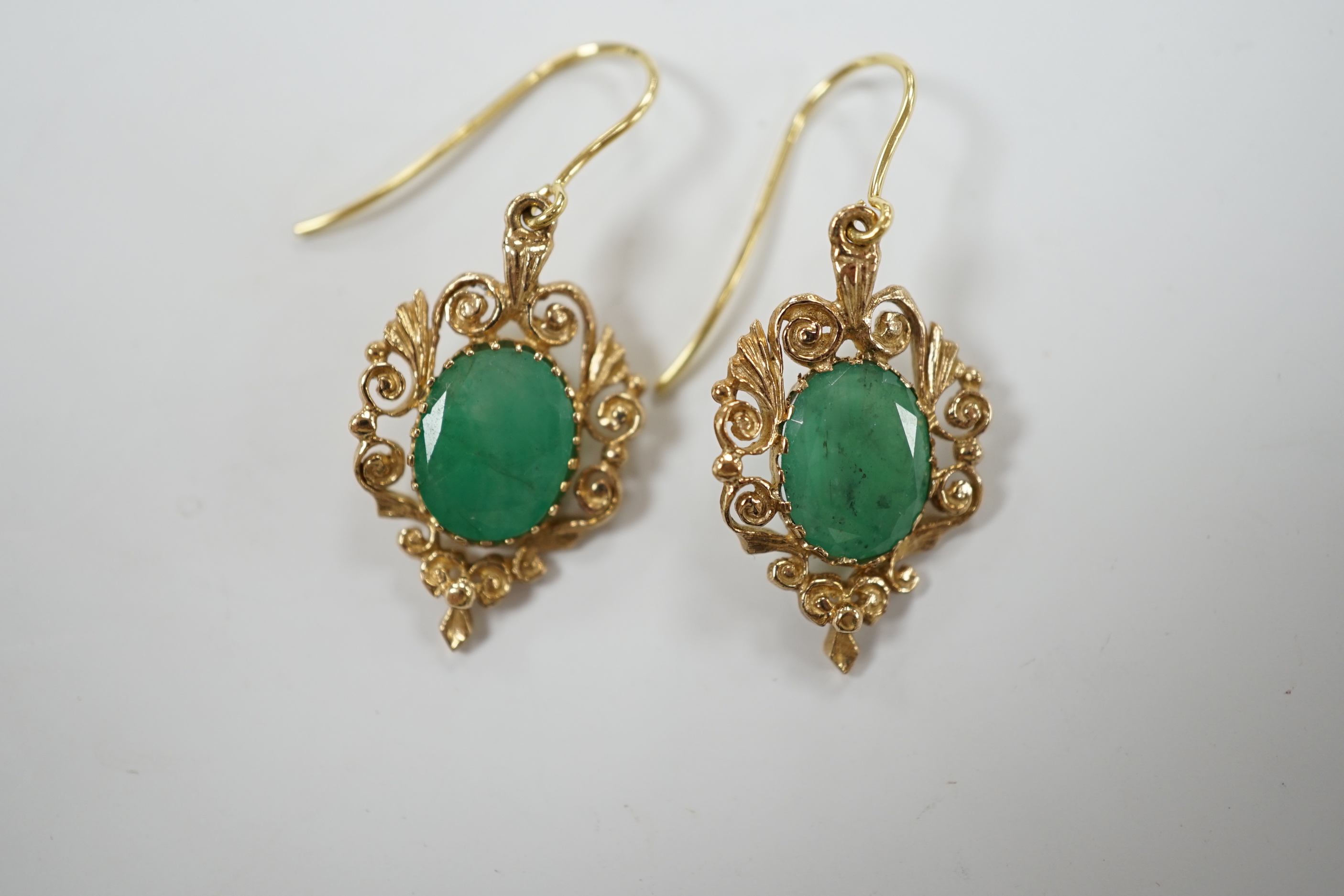 A pair of yellow metal and oval cut emerald set drop earrings, 23mm, gross weight 3.8 grams.
